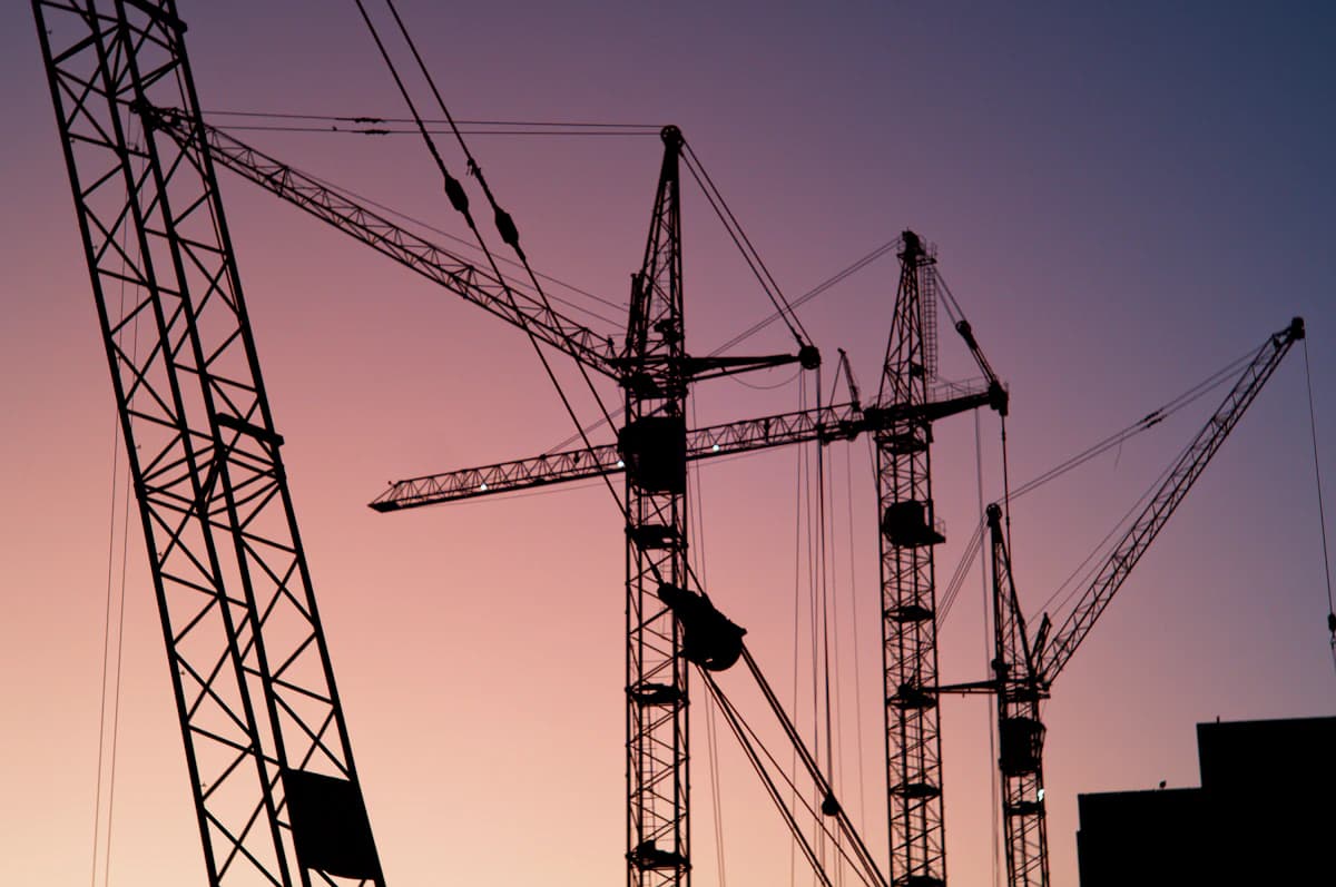 Tower cranes over a construction site at sunset