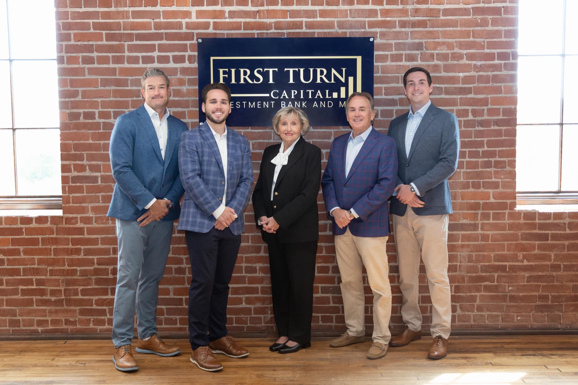 The First Turn Capital team standing in front of the firm's sign: Chad Godwin, Caleb Corbitt, Beverly Johnson, Doug Franklin, and Gray Katigan